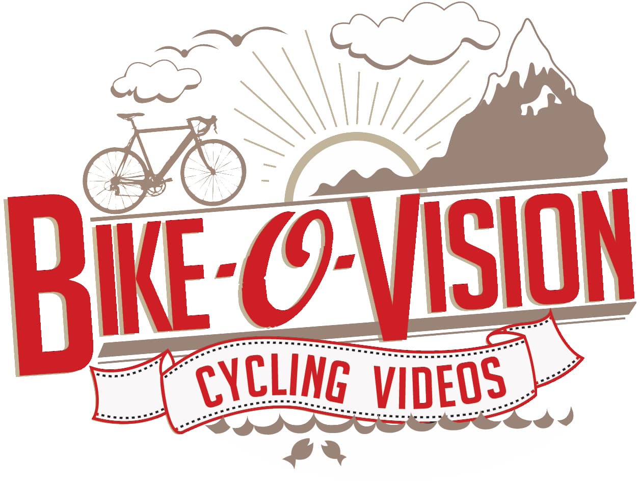 Logo for Bike-O-Vision Cycling Videos featuring a bicycle, a mountain, clouds, and a sunrise. The text is bold and red, with a ribbon banner displaying Cycling Videos below the main title.